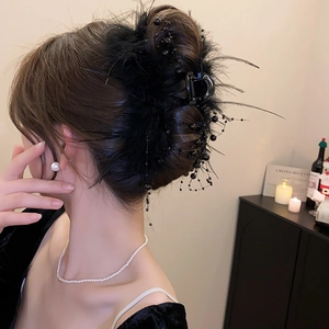 Detail of elegant black shark clip with feathers and bead chain on a woman's hairstyle