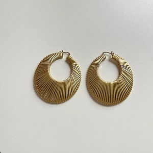 Détail de boucles d'oreilles dorées en forme d'éventail avec texture plissée radiale
