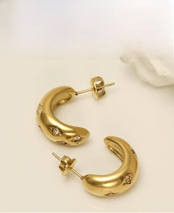 Detailed view of gold-plated C-shaped earrings with diamond inlay and star texture