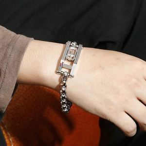 Close-up of hip hop silver chain bracelet with hollow cross rectangular charm on wrist