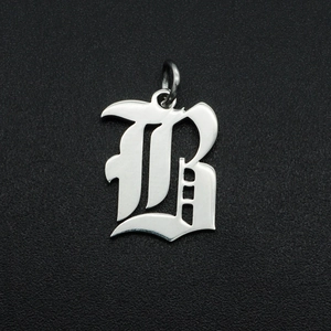 Macro shot of gothic letter B pendant in silver stainless steel on dark texture