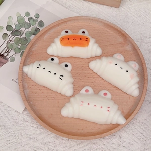 Cute cartoon cat croissant squishy stress relief toys on a wooden tray with lace cloth