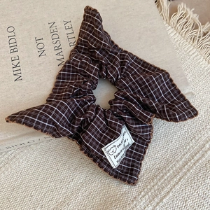 Close-up of brown plaid scrunchie fabric with dreamer label and bear detail