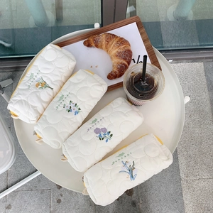 Gesteppte Stiftemappen mit Blumenstickerei auf weißem Tisch in einer Café-Szene