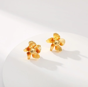 Elegant 18K gold plated floral brass stud earrings on minimalist white display stand