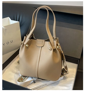 Close-up of beige bucket bag with litchi grain texture and ethnic pattern wide strap