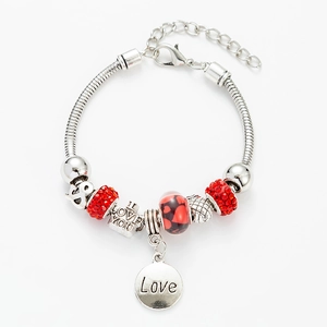Detailed view of the red crystal beads and heart-shaped charms on the silver LOVE bracelet