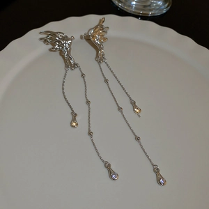 Dettaglio di orecchini a farfalla argentati con nappe lunghe e zirconi bianchi su piatto