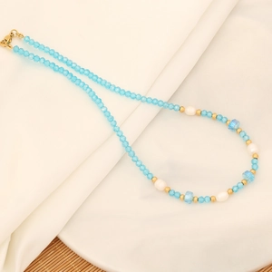 Detail of blue crystal bead necklace with white pearls and gold accents on white cloth