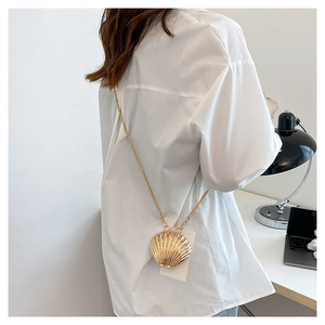 Close-up of golden shell crossbody bag with metal texture and pearl chain detail