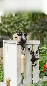 Detail of vintage cast iron deer head wall hooks mounted on rustic white wood paneling