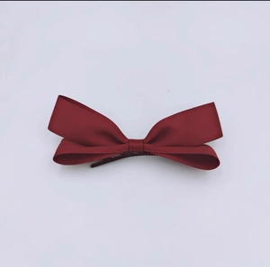 Close-up of a handmade red fabric bow hair clip featuring a high-quality 3D texture