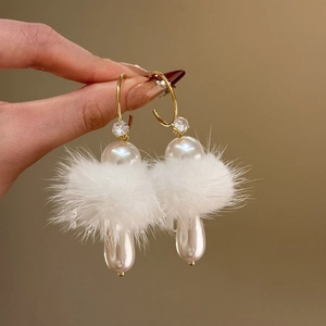 Detail of C-shaped gold earrings with white fur trim and hanging drop pearls