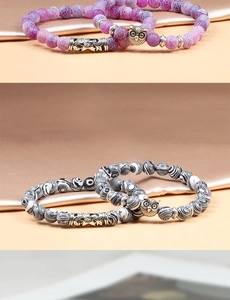Detail of beaded bracelets with purple and striped beads and silver owl charms