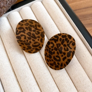 Macro detail of flocking leopard print round earrings resting in a soft jewelry box