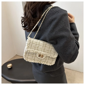 Detail of tweed crossbody bag featuring metal chain strap and elegant woven texture