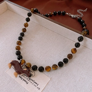 Detail of beaded necklace with tiger eye stones and cute dachshund dog resin pendant