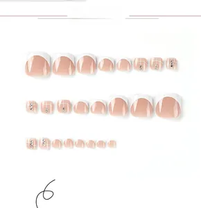 Macro view of French style white toe press-on nails with rhinestones and grid patterns