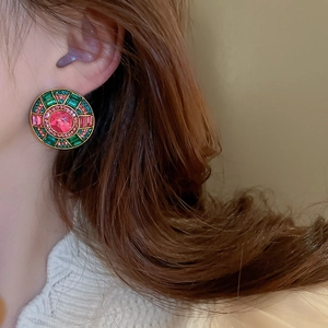 Detailed view of vintage gold stud earrings with pink and emerald green crystals on model