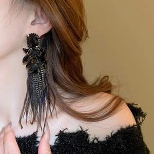 Macro view of gothic black flower earrings with sparkling rhinestones and long feathers