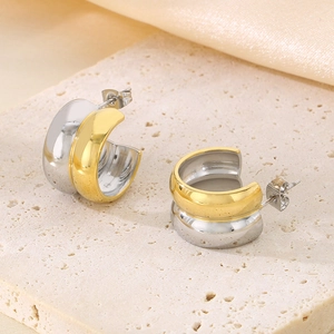 Vue détaillée des boucles d'oreilles en forme de C bicolores or et argent sur fond de soie
