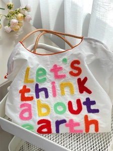 Detail of colorful towel embroidery and woven rope handle on a canvas tote bag