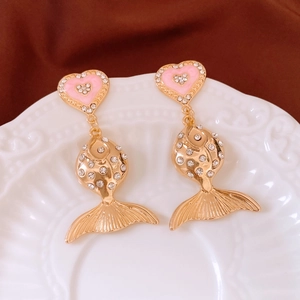 Close-up of vintage gold fish drop earrings with pink hearts and sparkling rhinestones