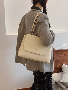 Minimalist beige leather shoulder bag with woven chain strap shown on model back