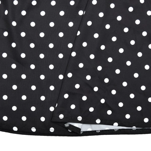 Gros plan de pois blancs sur tissu noir montrant les coutures soignées sur l'ourlet
