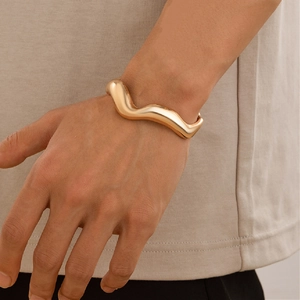 Chunky gold fluid wave bangle for men with a minimalist polished stainless steel finish
