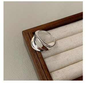 Macro shot of minimalist silver irregular wavy saddle ring on a fabric jewelry tray