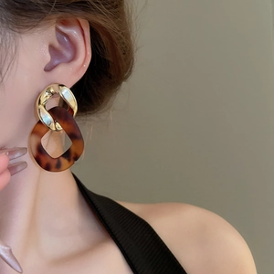 Detail of model wearing gold chain drop earrings with tortoiseshell resin links