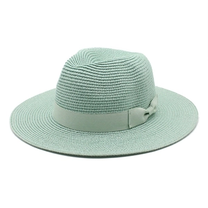 Detail of light green straw fedora hat featuring woven texture and bow ribbon decoration