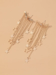 Detail view of gold star tassel earrings with elegant metal chains on a beige background