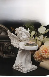 Detailed view of a white angel figurine holding a glass candle holder with candle