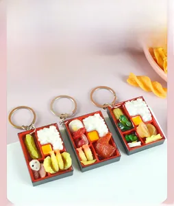 Detailed close-up of three miniature bento box keychains with realistic food models