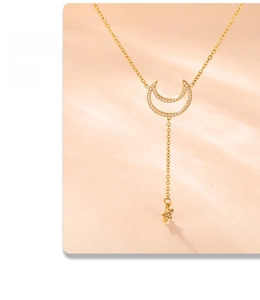 Detail of gold moon and star pendants with pavé zircon settings on a layered chain
