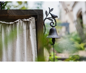 Detail of vintage cast iron doorbell with bird and leaf design against a rustic background