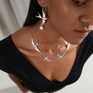 Nahaufnahme einer silbernen Schwalben-Halskette mit eleganten Perlenohrringen für Damen