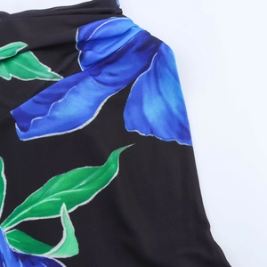Detailed view of black floral dress fabric showing blue blossoms and neckline stitching
