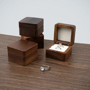Detailed view of square walnut wood ring boxes with white foam inserts for jewelry storage