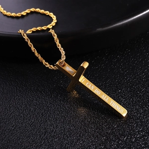 Macro detail of golden cross necklace showing engraved Bible verses on a twisted chain