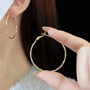 Close-up of elegant large golden hoop earrings with shiny polished metallic finish