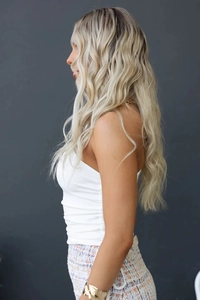 Détail d'un haut blanc moulant à une épaule avec les longs cheveux blonds de mannequin