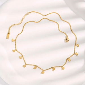 Elegant gold butterfly necklace with multiple charms on a white textured background