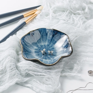 Close-up of blue ceramic jewelry tray with mottled glaze and elegant opal stud earrings