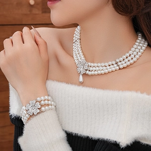 Detailed view of layered pearl necklace and bracelet with crystal clover and drop charm