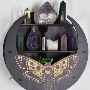 Close-up of crescent moon wooden shelf with moth engraving holding crystal stones