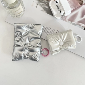Detail of quilted bow earphone cases in metallic silver and pearl white with snap button