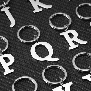 Set of creative silver metal alphabet keychains neatly arranged on a black background